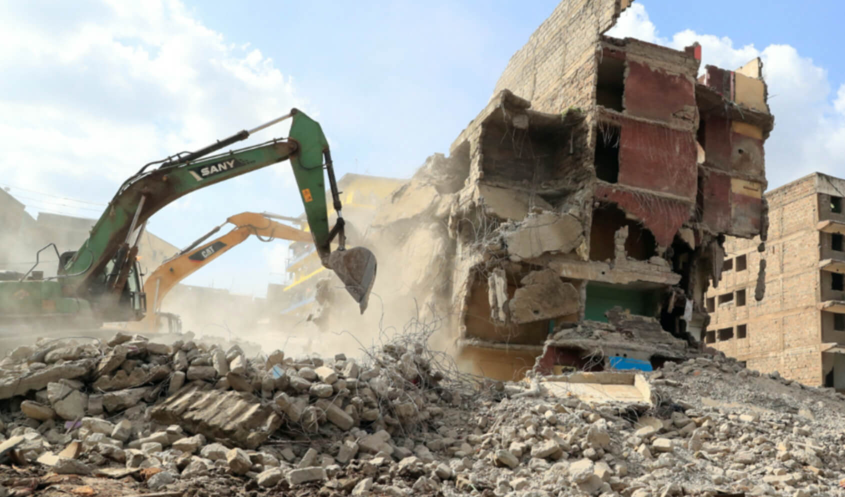 A bulldozer is demolishing a five story building in Mathare that was constructed in a riparian zone